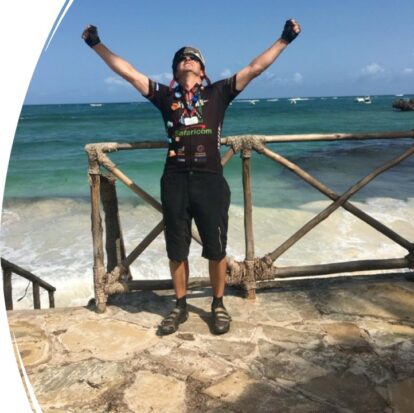 Ben Clay at the finish, arms raised, sea in the background
