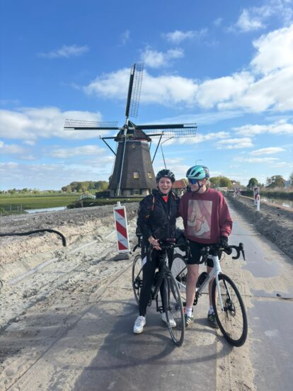 The two intrepid cyclists raising money for Empowering Kids in Kenya by cycling all the way from London to Holland, with a windmill in the background