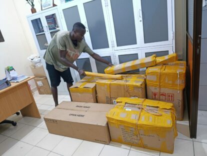 One of the staff with a group of boxes as the materials for the science lab begin to arrive