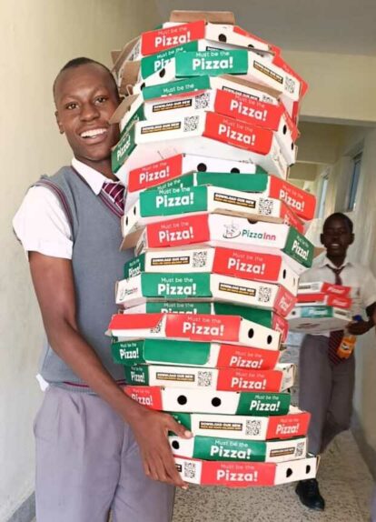 A student carrying a pile of pizza boxes
