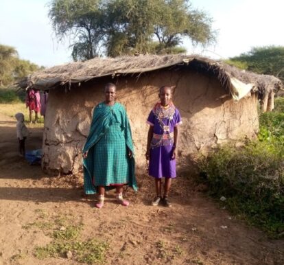 Rina standing withe her mother standing outside their Maasi home